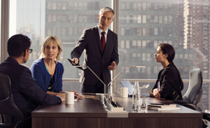 Image of a meeting, wherein four colleagues gather around a desk to discuss a project.