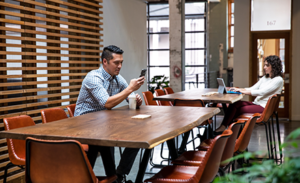 Image of two workers working at separate tables in a casual office environment.