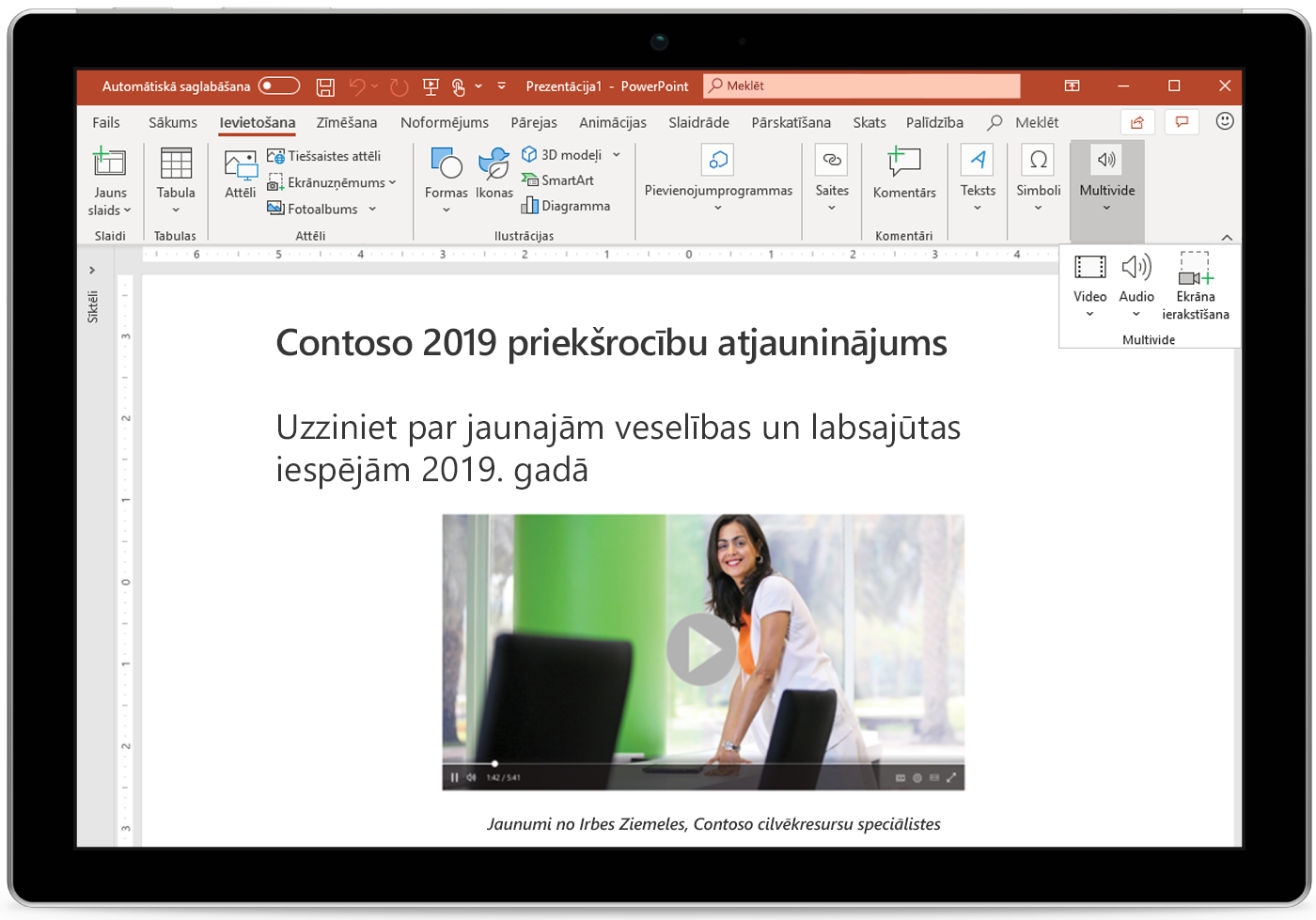 Attēls ar planšetdatoru, kurā redzams PowerPoint slaids.