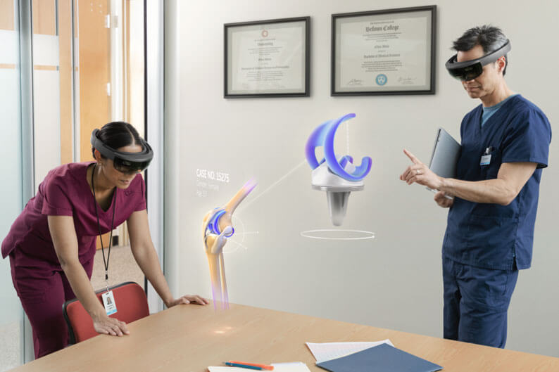 Two healthcare workers testing Microsoft HoloLens with holograms in the foreground.
