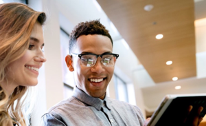 Two coworkers look over a document on a tablet.