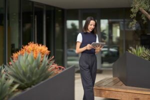 Uma mulher que participa de uma reunião do Microsoft Teams em seu tablet Surface enquanto caminha pelo pátio externo de seu escritório.