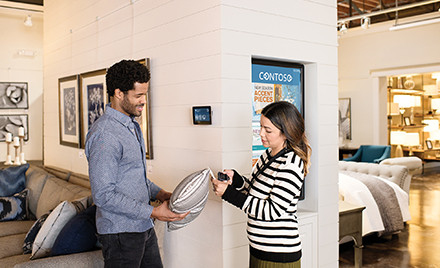 Two firstline workers examine a pillow in a shop.